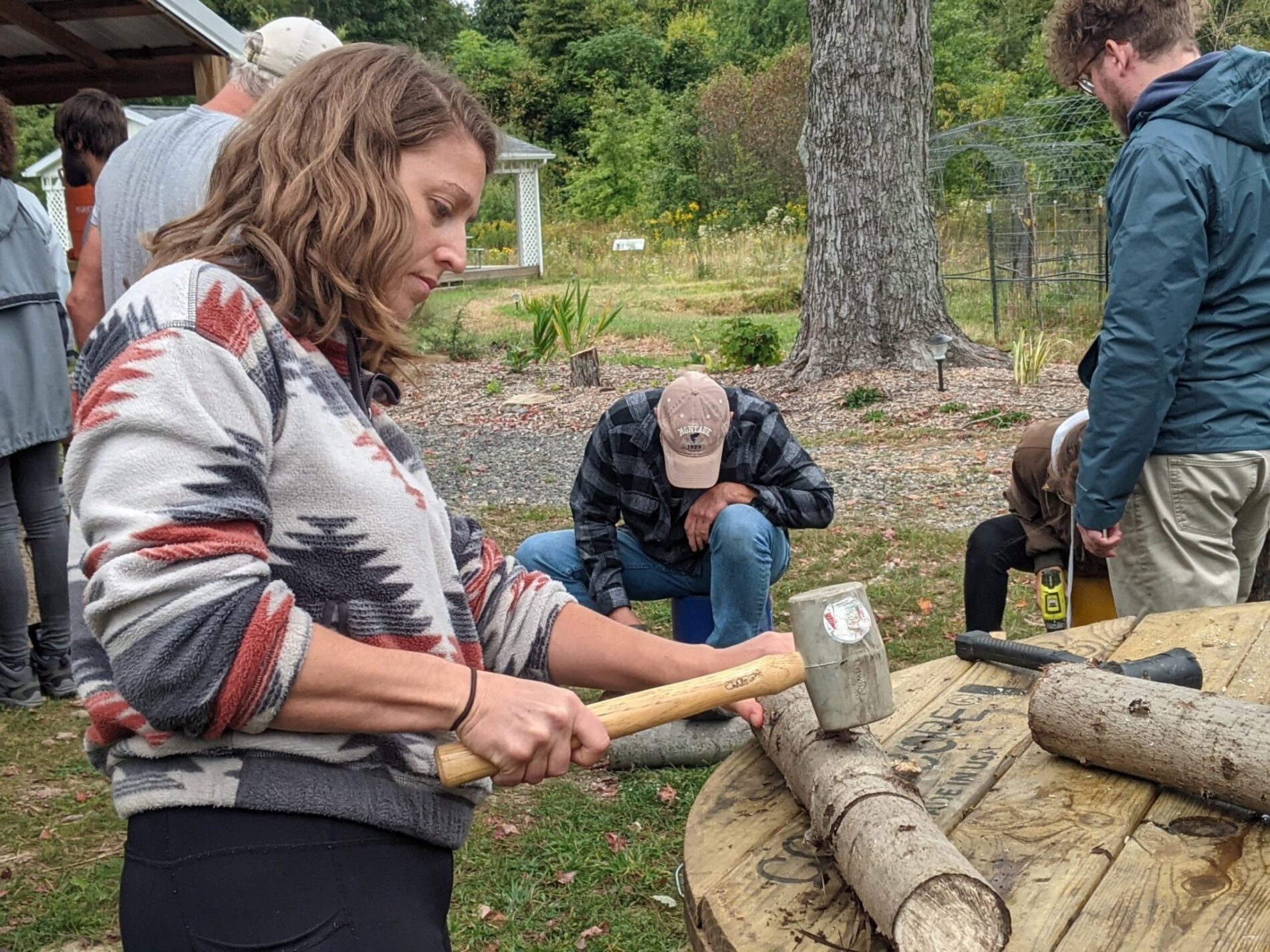 Students making mushroom logs during an in-person PDC